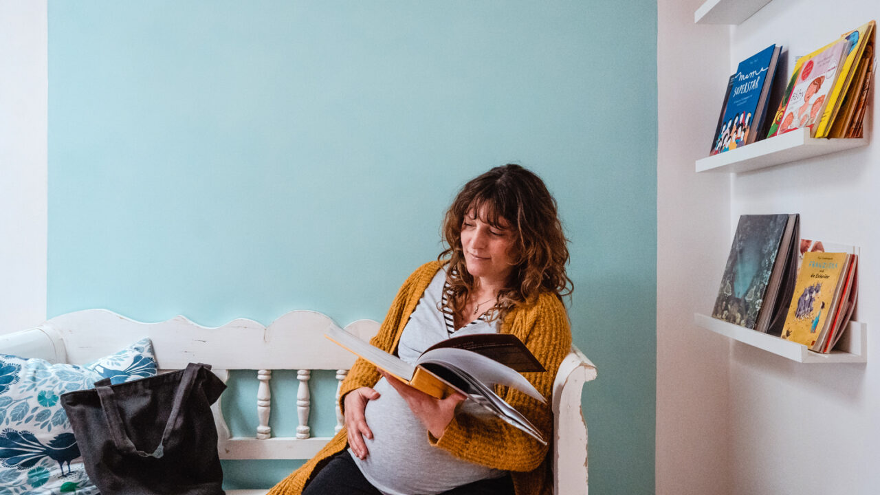 Eine Schwangere Person liest ein Buch in der Praxis