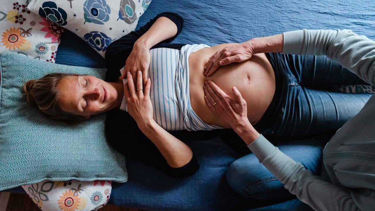 Der Bauch einer Schwangeren Person wird abgetastet